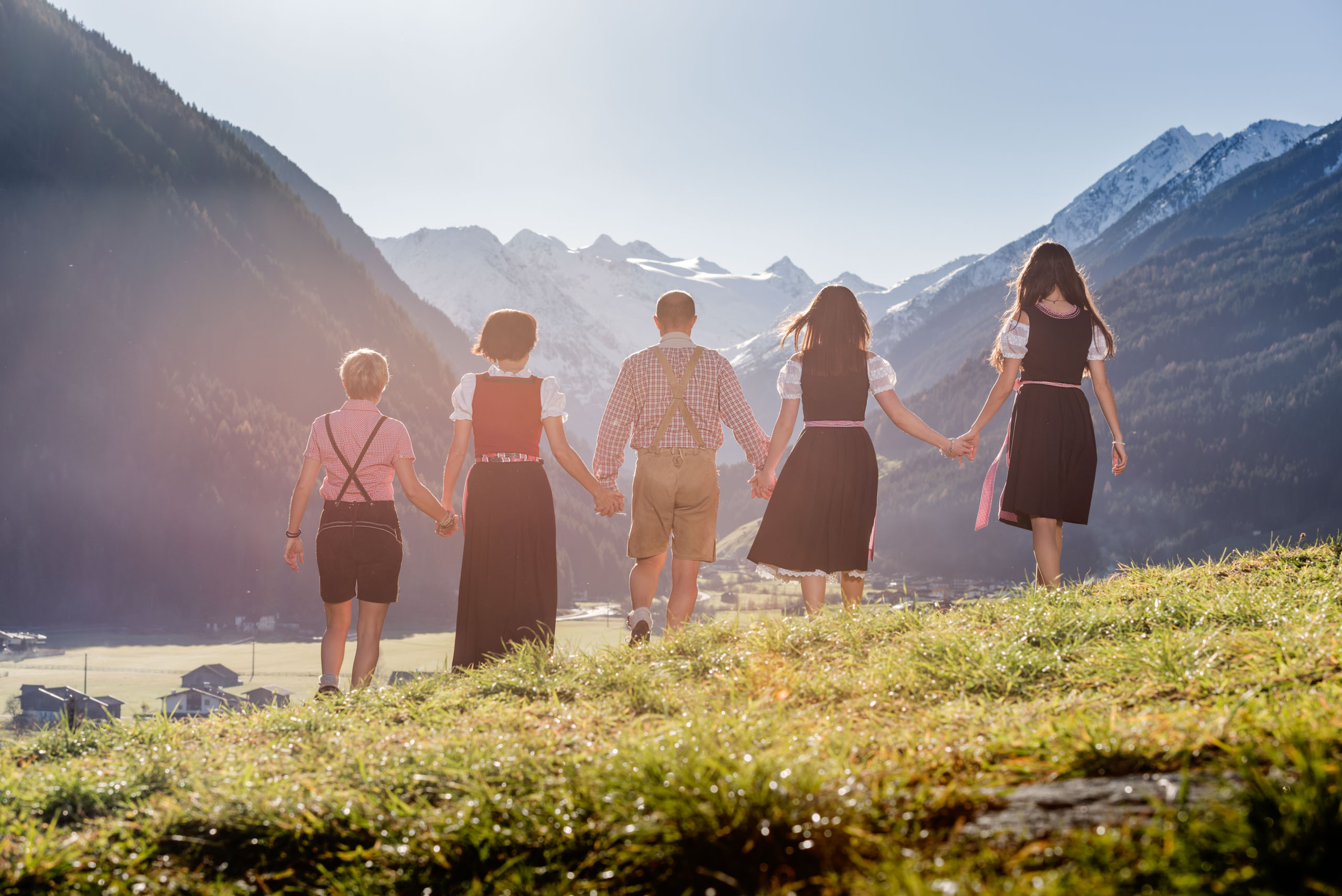 Familie Stern, trachtig gekleidet, geht Hand in Hand im Stubaital auf einer Wiese